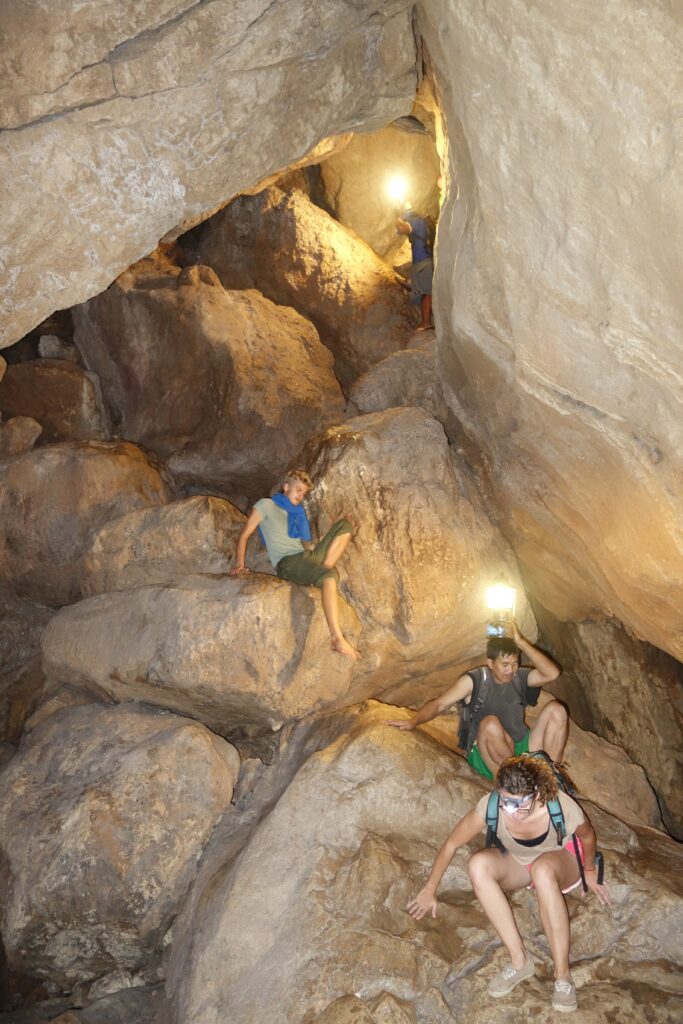 A larger chamber in the cave with other members of our group climbing down some rocks.