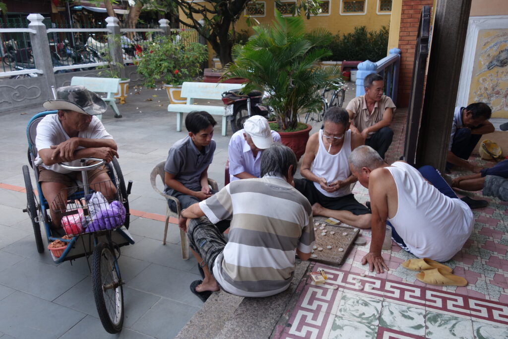 A group playing Chinese chess outside of a temple in Hoi An